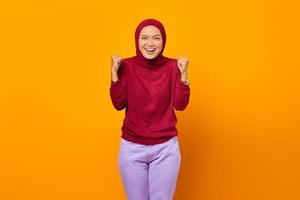 Aufgeregte asiatische muslimische Frau, die den Sieg mit einem Lächeln nach vorne feiert foto