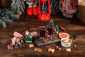 Weihnachtsglühwein mit Gewürzen und Früchten auf einem dunklen Tisch. foto