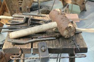 Kunst Zimmerei Werkstatt mit Hammer, hölzern Stücke und Bretter, Hand Werkzeuge und hölzern Arbeit Bank im das Vordergrund. Tischlerei mit Werkbank und viele von Holz. Tischler Tabelle mit Möbel Einzelheiten foto