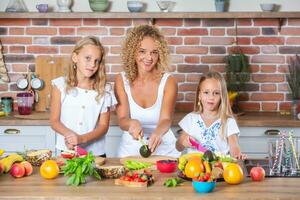 Mutter und Töchter Kochen zusammen im das Küche. gesund Essen Konzept. Porträt von glücklich Familie mit frisch Smoothies. glücklich Schwestern. foto