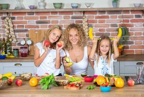 Mutter und Töchter Kochen zusammen im das Küche. gesund Essen Konzept. Porträt von glücklich Familie mit frisch Smoothies. glücklich Schwestern. foto