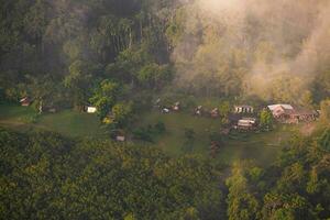 das atemberaubend Aussicht von ein Touristen Standpunkt wie Sie gehen Nieder ein Hügel auf ein nebelig Weg mit ein Hügel und ein Hintergrund von ein golden Himmel im Wald Park, Thailand. Vogel Auge Sicht. Antenne Sicht. foto