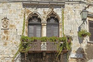 Bild von ein Balkon mit Metall Balustrade und Türen mit braun Fensterläden auf ein Antiquität Fassade foto