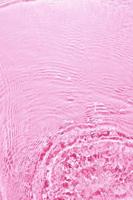 Textur des Spritzens von sauberem Wasser auf rosa Hintergrund foto