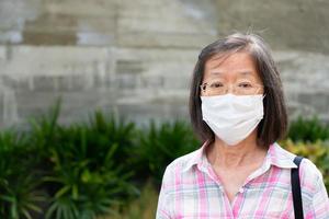 ältere asiatische frau, die maske trägt, während sie nach draußen geht