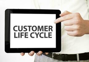 Text Kunde Leben Zyklus auf Tablette Anzeige im Geschäftsmann Hände auf das Weiß Hintergrund. Geschäft Konzept foto