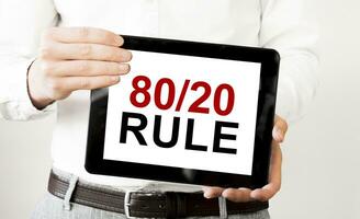 Text 80 und 20 Regel auf Tablette Anzeige im Geschäftsmann Hände auf das Weiß Hintergrund. Geschäft Konzept foto