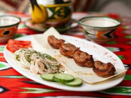 Hähnchen Kebab Holzkohle gegrillt Hähnchen Brust serviert mit Gemüse, eingelegt Zwiebeln, Lavash Brot und orientalisch Soße foto