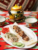 Hähnchen Kebab Holzkohle gegrillt Hähnchen Brust serviert mit Gemüse, eingelegt Zwiebeln, Lavash Brot und orientalisch Soße foto