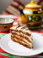 Dessert Schokolade Kuchen mit Beige Sahne im orientalisch Stil auf ein Dach mit ein Teekanne und ein Tasse zum Tee. foto