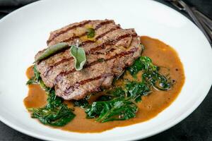 Rindfleisch Steak mit Soße und Kräuter auf ein Weiß Teller foto