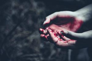 Nahaufnahme von blutigen Händen im dunklen Waldhintergrund foto