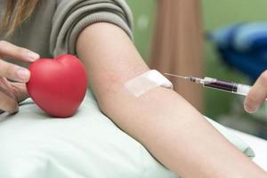 Blutentnahme durch Krankenschwester im Krankenhaus mit rotem Herzen foto