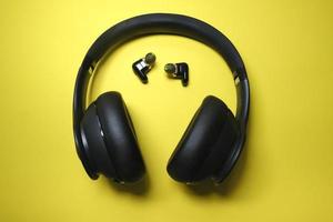 schwarzer Kopfhörer und winzige Ohrhörer auf gelbem Hintergrund foto
