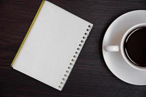 Draufsicht auf Kaffeetasse und leeres Notizbuch für Memo