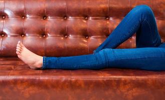 Frauenbeine mit Jeans beim Entspannen im Kino