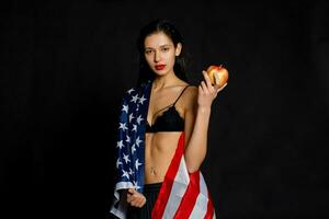 Porträt weiblich Athlet eingewickelt im amerikanisch Flagge gegen schwarz Hintergrund foto