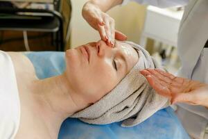 schön jung Frau Empfang Gesichts- Massage mit geschlossen Augen im ein Spa Salon foto
