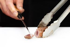 Koch schneidet gegrilltes Fleisch an Bord in der Küche foto