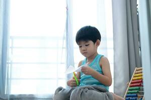 asiatisch Junge mit Schere zu Schnitt Papier entlang Linien Lernen draußen das Klassenzimmer foto
