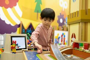 wenig asiatisch Junge spielen mit Spielzeug Auto im das Kinder- abspielen Park foto