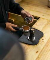 Barista bereiten zu Drücken Sie Kaffee manipulieren zu machen Espresso. bewirbt sich Druck auf ein Kaffee mahlt auf Stampfen Maschine Vor Erstellen Espresso basierend Kaffee eine solche wie Cappuccino, Latté, oder Amerikaner. foto