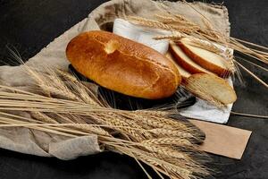 ganze und geschnitten Weiß Brot mit Ohren von Weizen und Sackleinen foto