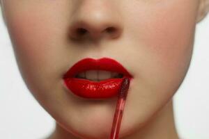jung Frau bewirbt sich rot Lippenstift zu ihr Lippen, weiblich Gesicht Nahaufnahme. foto