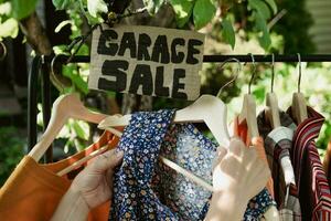 Garage Verkauf. weiblich Hände pflücken aus benutzt bekleidung hängend auf Gestell. foto