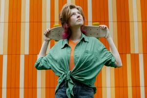 attraktiv Skater jung Frau mit Skateboard gegen städtisch Mauer. foto