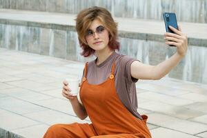 gen z weiblich Blogger nehmen Selfie mit Smartphone Gehen um Stadt. foto