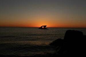 diese ist das schön Bild von das versunken Schiff von Kap kann Neu Jersey während Sonnenuntergang. das Himmel hat schön Farben von Orange fast mögen es ist auf Feuer. das feurig Schatten reflektieren aus das Wasser. foto