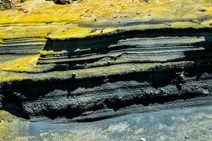 ein Gelb und schwarz Felsen Formation auf das Strand foto