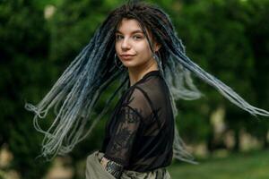 heiter kaukasisch Mädchen suchen beim das Kamera und lächelnd Modell- mit Dreadlocks foto