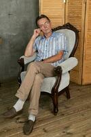 ein alt intelligent Mann haben ein sich ausruhen auf ein Sessel foto
