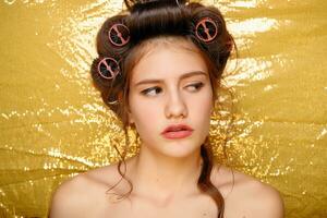 schön Mädchen im Haar Lockenwickler isoliert auf Gold foto