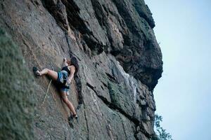 ein Mädchen klettert ein Felsen. Frau beschäftigt, verlobt im extrem Sport. foto