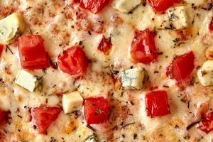 Makro Schuss von Pizza mit Tomaten, Gorgonzola, geschmolzen Mozzarella und getrocknet Basilikum foto