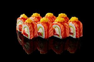 Uramaki rollen mit Sahne Käse, Tobiko, Avocado, angebraten Lachs, Mango auf schwarz Hintergrund foto