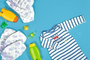 Baby Pflege mit Bad Satz. Nippel, Spielzeug, Kleidung, Shampoo auf Blau Hintergrund oben Aussicht Attrappe, Lehrmodell, Simulation foto