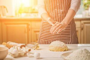 Frau schlagen seine Hände über Teig Nahaufnahme. Bäcker Fertigstellung seine Bäckerei, Shake Mehl von seine Hände, kostenlos Raum zum Text. foto