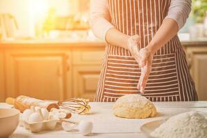 Frau schlagen seine Hände über Teig Nahaufnahme. Bäcker Fertigstellung seine Bäckerei, Shake Mehl von seine Hände, kostenlos Raum zum Text. foto