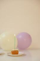 Geburtstag Cupcake mit Kerze und Luftballons auf Tisch. selektiv Fokus. foto