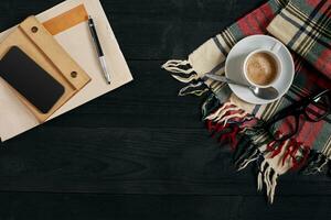 Arbeitsplatz mit Zeitung, Kaffee Tasse, Schal, Brille. stilvoll Büro Schreibtisch. Herbst oder Winter Konzept. eben legen, oben Aussicht foto