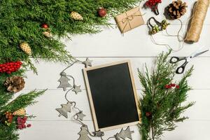 Wacholder Geäst mit ein Weihnachten Dekor. Weihnachten, Neu Jahr Hintergrund. Nadelbaum Geäst von Wacholder und schwarz Schreiben Tafel. oben Sicht, eben Design. foto