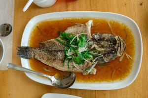 Dampf gebraten marmoriert Vergehen Fisch namens ikan Malas im Siamese Stil serviert im ein Gericht auf ein hölzern Tabelle im ein Restaurant im Indonesien foto
