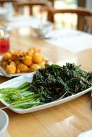 gebraten gekocht Grün Gemüse namens Kailan serviert auf ein Restaurant Essen Tabelle mit ein Weiß Teller foto