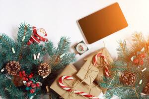 Weihnachten online Einkaufen Hintergrund. Tablette Bildschirm mit Kopieren Raum, Fichte Geäst, Geschenke auf Weiß Hintergrund. Sonne Fackel foto