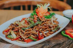 gebraten Udon Meeresfrüchte mit Gemüse. serviert im Weiß Teller mit Hand und Tabelle von das Restaurant foto