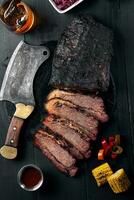 frisch Bruststück Grill Rindfleisch geschnitten zum Portion gegen ein dunkel Hintergrund mit Soße, heiß Pfeffer und Mais. foto